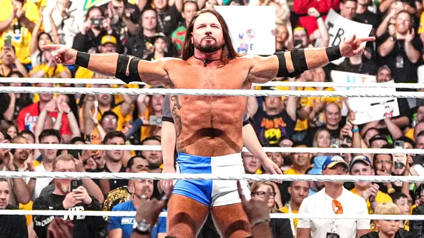 AJ Styles stands in the WWE ring with arms raised as fans cheer during a major live event.
