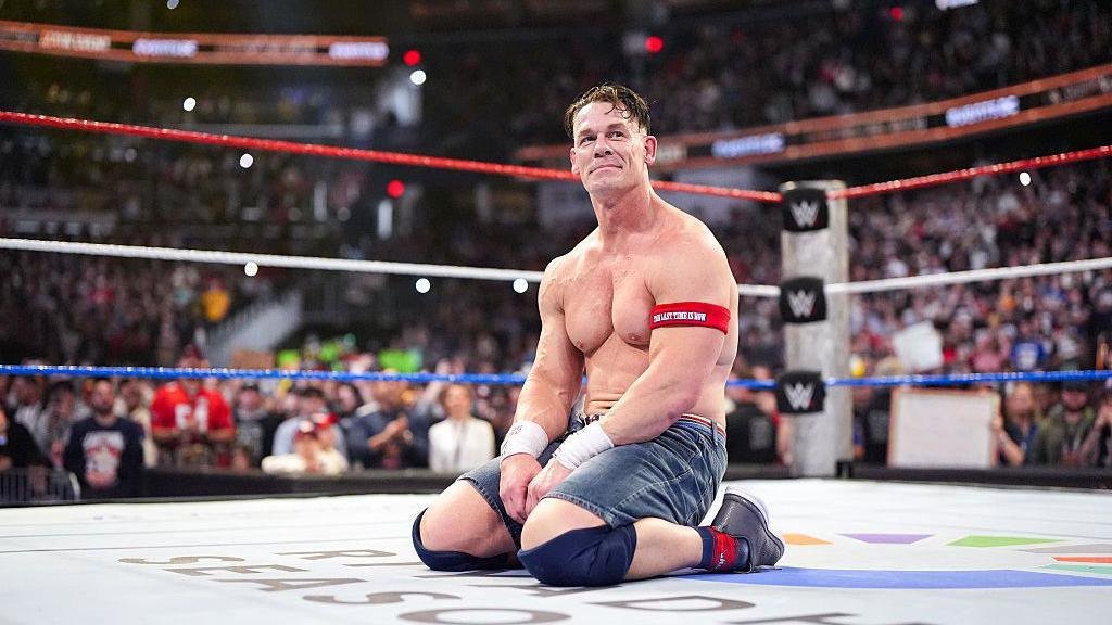 WWE superstar kneels inside the ring after an emotional match as fans look on