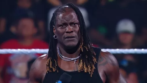 Professional wrestler R-Truth looks confused while standing in a wrestling ring during a WWE event.