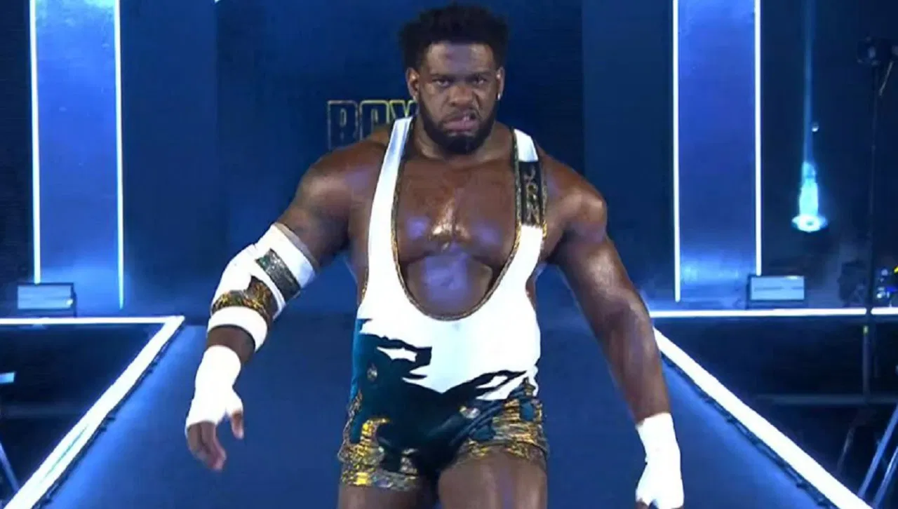 Muscular professional wrestler making his entrance on WWE stage wearing a white and gold singlet.