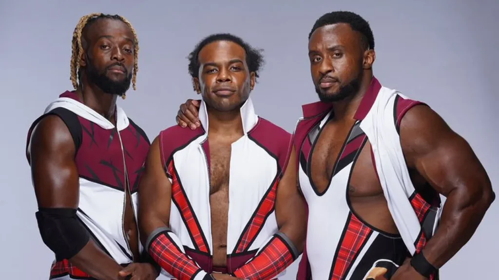 A promotional photograph of the three members of The New Day wrestling stable: Kofi Kingston, Xavier Woods, and Big E, posing in matching maroon and white vests.