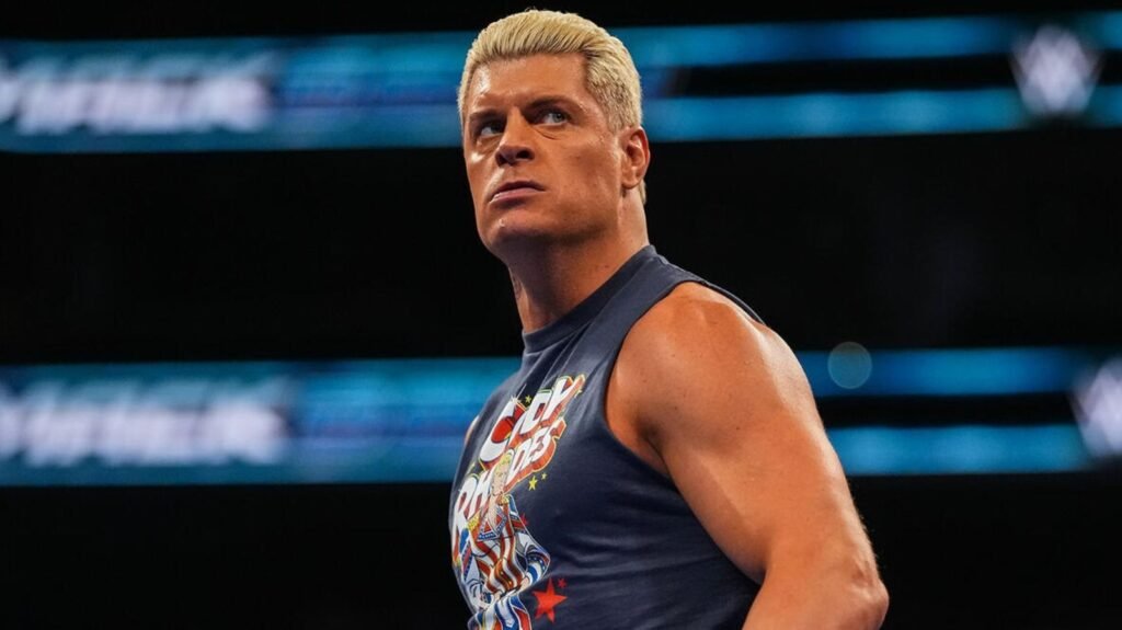 Cody rhodes stands inside a wwe ring during a televised event, looking focused while wearing a sleeveless “cody rhodes” graphic shirt. - tjr wrestling