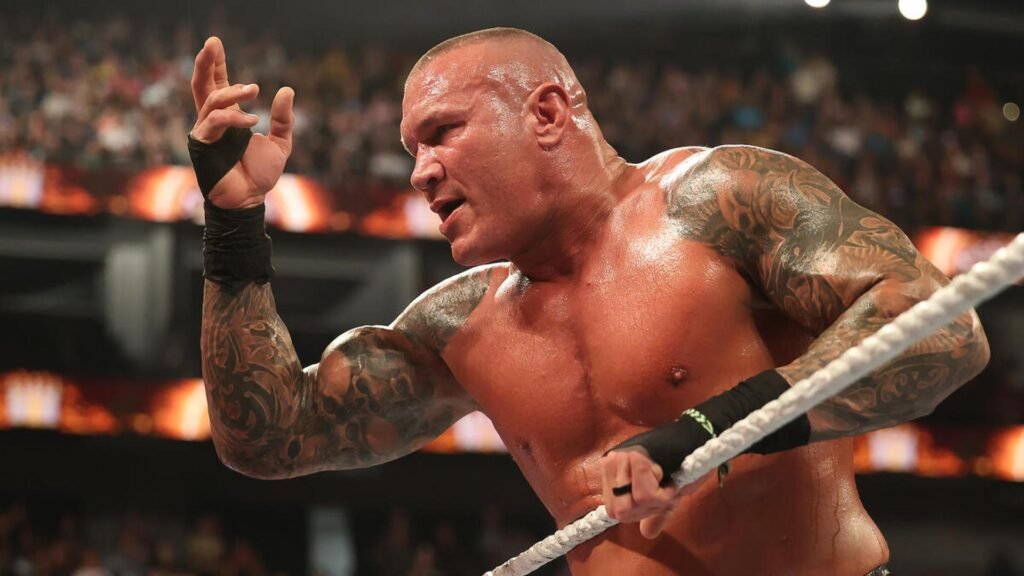 Randy orton makes dramatic wwe entrance - tjr wrestling Randy orton walks toward the ring under red lighting, wearing white trunks with a focused and intense expression.