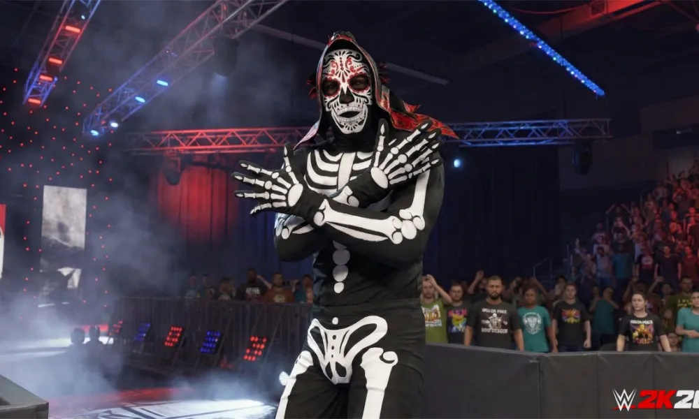Wwe 2k26 reveals stunning lucha legend with jaw-dropping skeleton look - tjr wrestling A wwe 2k26 video game screenshot showing a lucha libre wrestler character wearing a black and white skeleton bodysuit and a colorful day of the dead style face mask, standing in a dramatic entrance pose on the ramp with fog, red and blue arena lights, and a crowd of fans visible in the background.