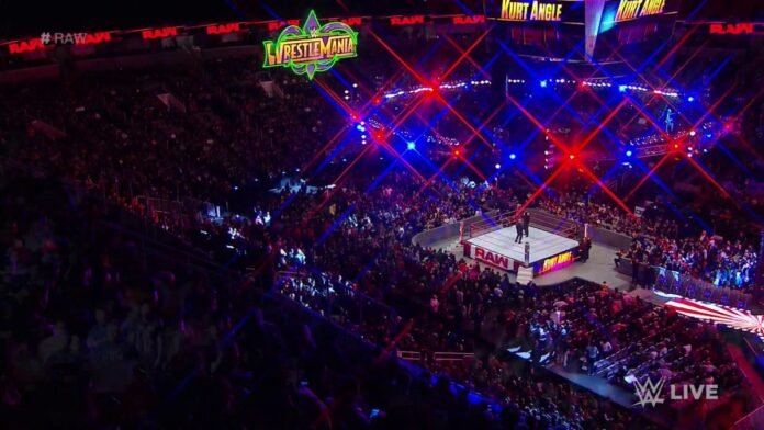 A packed WWE RAW arena with the wrestling ring set up under bright red lights as thousands of fans fill the venue before the live show.