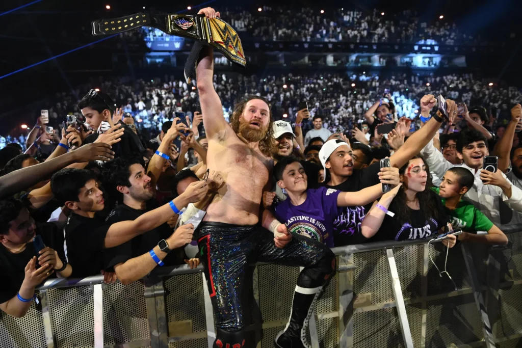Sami zayn celebrates with the wwe championship while standing among fans after winning the title at wwe night of champions 2026. - tjr wrestling