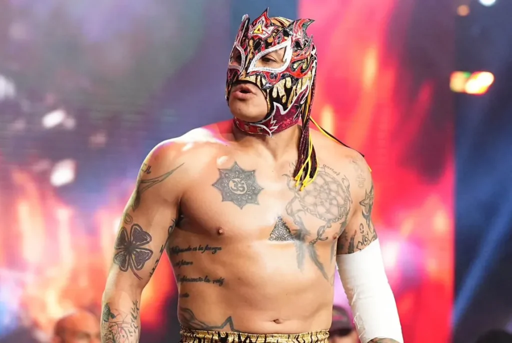 Rey fenix entrance during wwe nxt broadcast - tjr wrestling Luchador wrestler rey fenix strikes a pose on the entrance ramp wearing a vibrant, flame-patterned mask and vest amidst colorful stage laser lights.