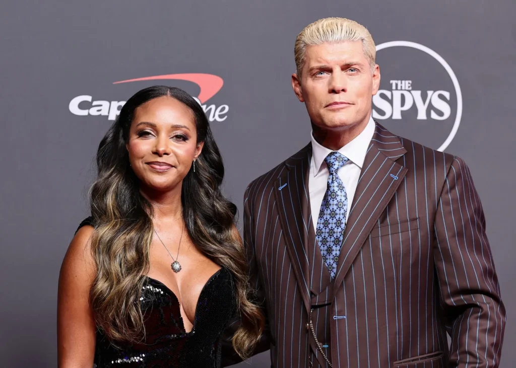 Brandi rhodes in a black dress and cody rhodes in a brown pinstripe suit posing on the red carpet at the espy awards. - tjr wrestling