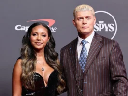 Brandi Rhodes in a black dress and Cody Rhodes in a brown pinstripe suit posing on the red carpet at the ESPY Awards.