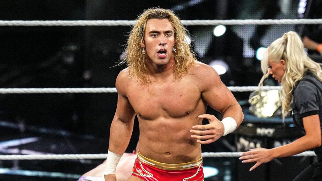 Wwe nxt wrestler tristan angels standing inside the ring with long blonde hair, red trunks, and a surprised expression during a match. - tjr wrestling
