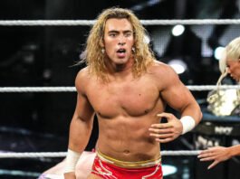 WWE NXT wrestler Tristan Angels standing inside the ring with long blonde hair, red trunks, and a surprised expression during a match.