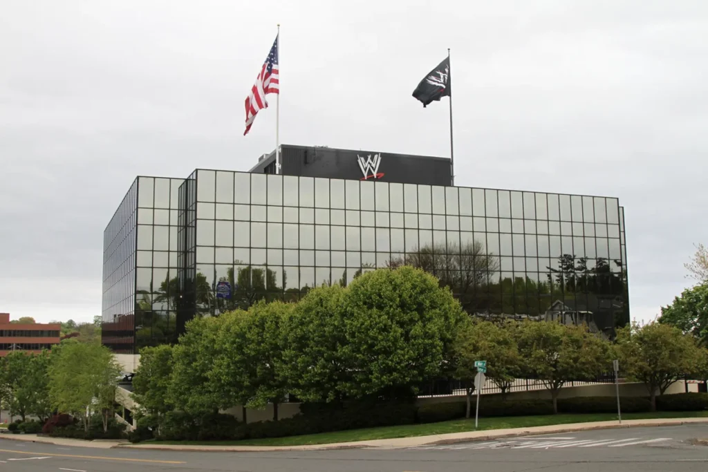 Wwe corporate headquarters exterior view - tjr wrestling Exterior view of a modern glass-paneled building with the wwe logo on top and american and company flags flying.
