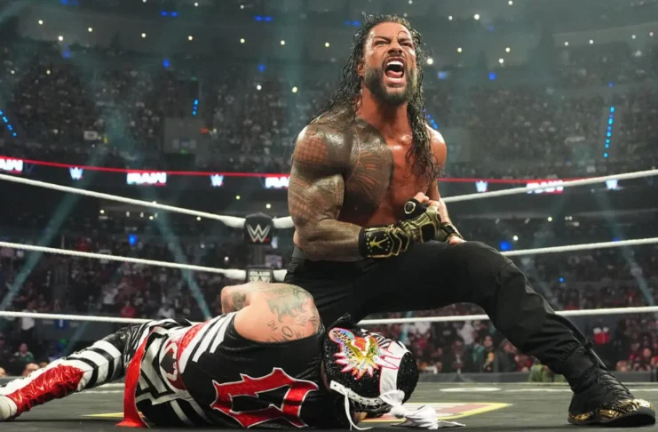 WWE Superstar Roman Reigns roaring in victory over a fallen Penta inside a packed wrestling arena ring.